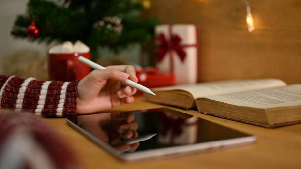 istock close-up image, A female using her digital tablet, working at her desk in Christmas theme. 1444399339