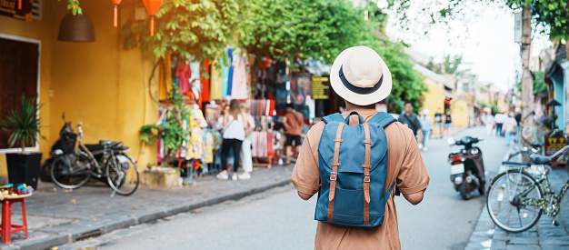 happy Solo traveler sightseeing at Hoi An ancient town in central Vietnam, man traveling with backpack and hat. landmark and popular for tourist attractions. Vietnam and Southeast Asia travel concept