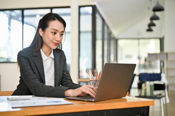 istock Professional Asian female accountant using laptop, typing on keyboard, working in her office. 1444402299