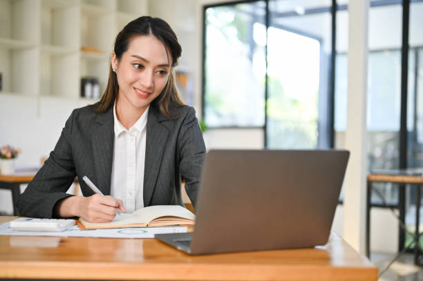 istock Asian female secretary or assistant writing or taking notes in her notebook while working 1444402300