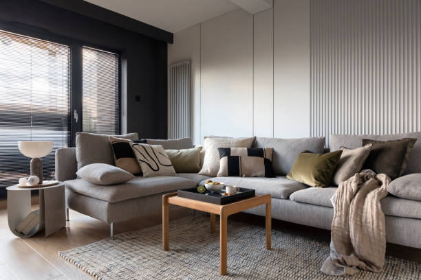 istock Creative composition of living room interior with design gray sofa, wooden coffee table, stylish carpet, beige side table, pillows, personal accessories and marble lamp. Stylish home decor. Template. 1444402907