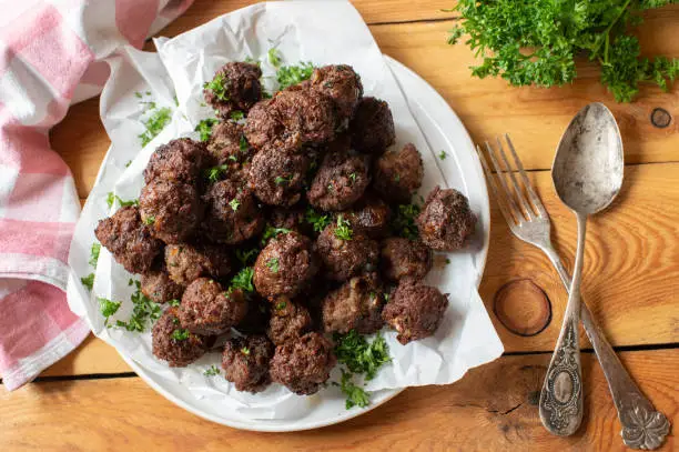 Homemade fresh pan fried beef meatballs. Served on a pile on rustic and wooden table background from above