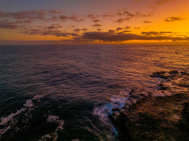 Dawn by the ocean with rocks Aerial sunrise at the seaside with rocks and gentle surf at Avoca Beach on the Central Coast, NSW, Australia. avoca beach photos stock pictures, royalty-free photos & images