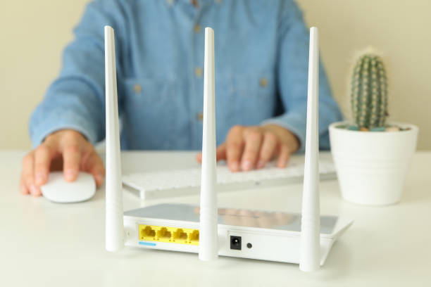 istock Wi-fi router and woman using computer on white table 1444406374