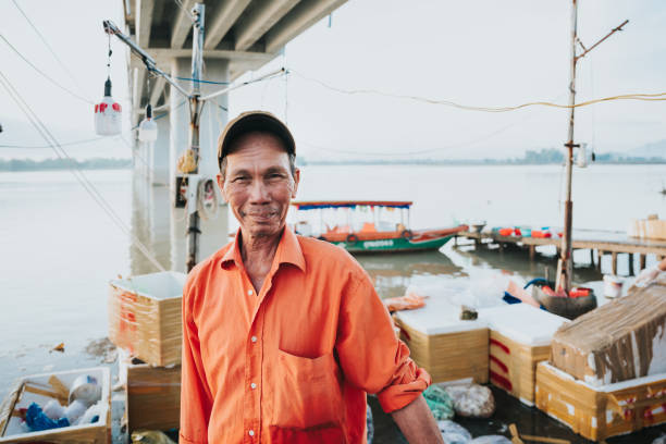 ritratto del pescatore anziano al mercato del pesce in vietnam - fishermen harbor foto e immagini stock