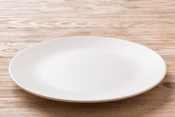 istock Perspective view of empty light plate on wooden background. Empty space for your design 1444407986