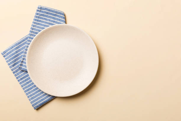 Top view on colored background empty round white plate on tablecloth for food. Empty dish on napkin with space for your design