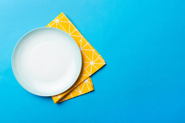 istock Top view on colored background empty round blue plate on tablecloth for food. Empty dish on napkin with space for your design 1444408069