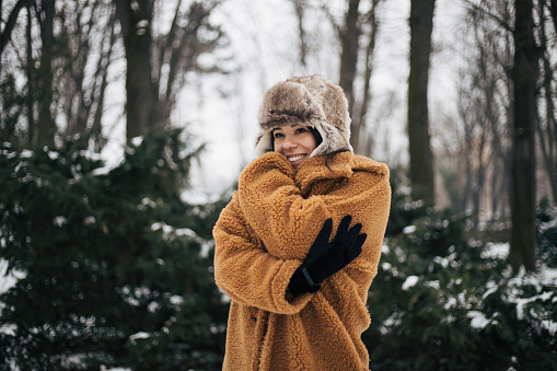 Beautiful smiling young woman in warm clothing. The concept of portrait in winter snowy weather.