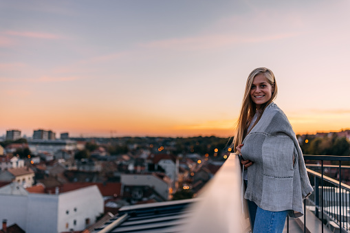 Happy blonde girl, posing for the camera, being on the roof terrace.