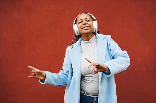 Happy african senior woman dancing in winter time outdoor - Focus on face