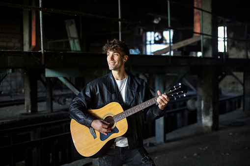 Young male musician posing with his acoustic guitar. About 25 years old, Caucasian man.