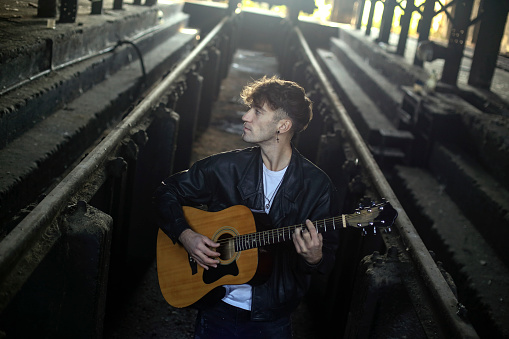 Young male musician posing with his acoustic guitar. About 25 years old, Caucasian man.