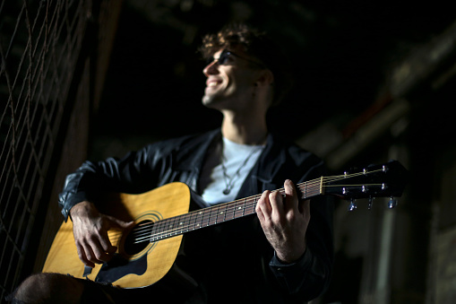 Young male musician posing with his acoustic guitar. About 25 years old, Caucasian man.