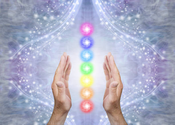 Sensing Seven Chakras and Sending Healing Male parallel hands with 7 rainbow coloured energy centres between against a blue flowing sparkling background and copy space reiki stock pictures, royalty-free photos & images