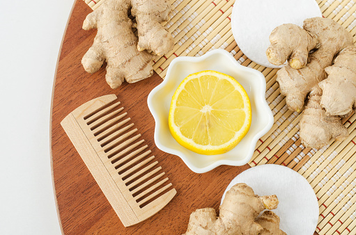 Lemon slice, ginger roots and wooden hairbrush. Ingredients or preparing homemade beauty mask. Top view, copy space.