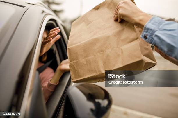 Customer Receiving Coffee And Takeaway Food Order From A Service Person At The Drive Through Stock Photo - Download Image Now