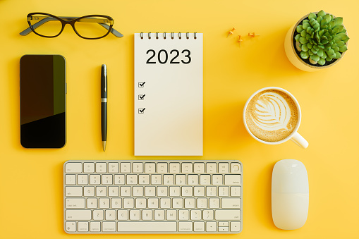 2023 New Year Goals Concept. Top View Of Computer Keyboard, Mouse, Smart Phone, Succulent Plant And Coffee Cup On Yellow Background