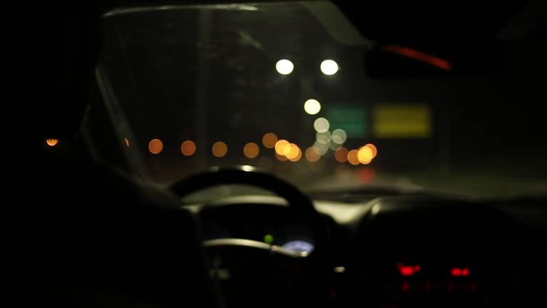 A man driving a car at night on the highway, view from the cabin from the back seat