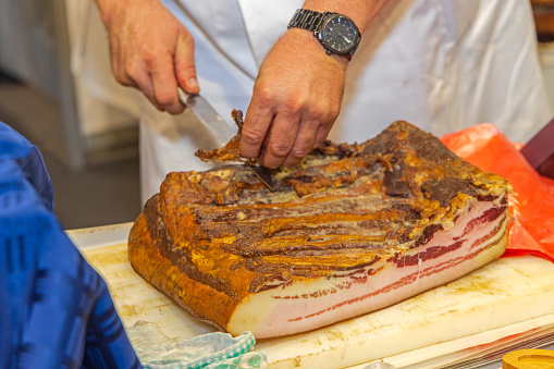 Cutting Large Slab of Pork Bacon Meat at Table