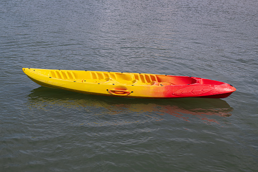 lonely yellow and red sit on top kayak in the middle of calm and calm sea water