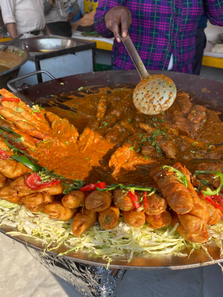 zdjęcie nierozpoznawalna osoba serwująca uliczne jedzenie, chrupiąca soja chaap (paluszki sojowe) podawana z sosem curry, zielonymi chilli i pokrojonymi pomidorami, street food przygotowany na tawa (duża, płaska metalowa patelnia), tradycyjne indyjski - chaap zdjęcia i obrazy z banku zdjęć