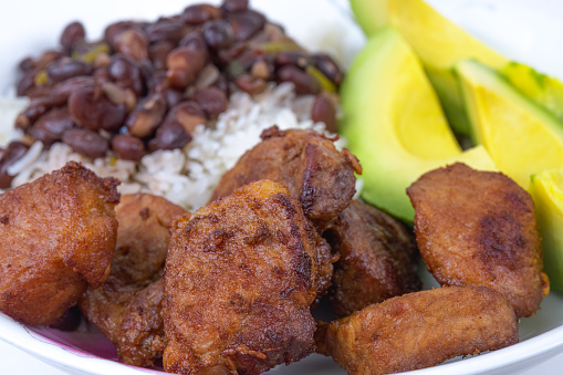 Deep fried pork meat, avocado slices, rice and black beans. All cooked the creole Cuban style. Studio shot