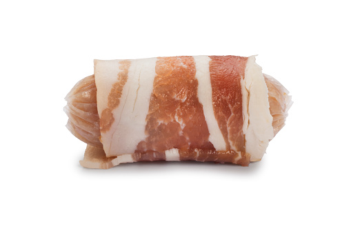 Studio shot of raw sausages wrapped with bacon know as pigs in blankets cut out against a white background