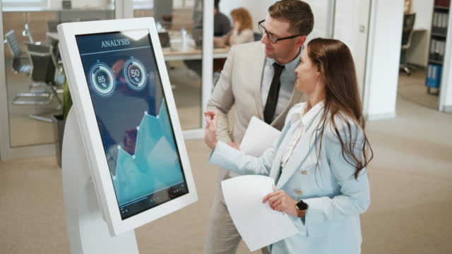 Business people using interactive touchscreen display with charts