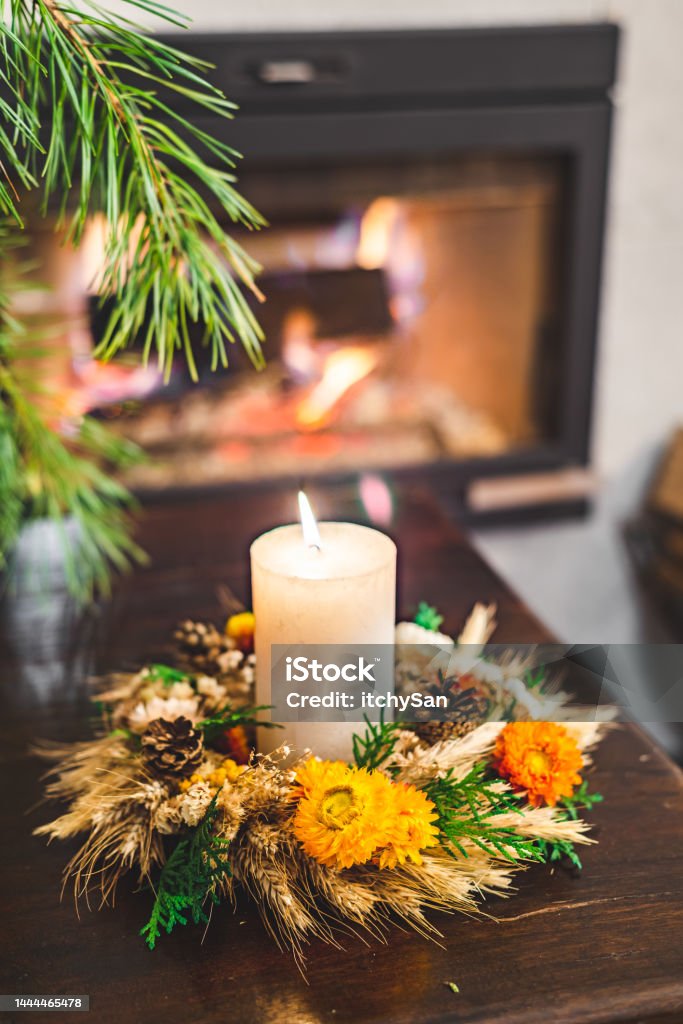 Candle and christmas wreath Handle lighting a candle. In a beautiful, hand made wreath. On an old wooden table in front of a fireplace. Art And Craft Stock Photo