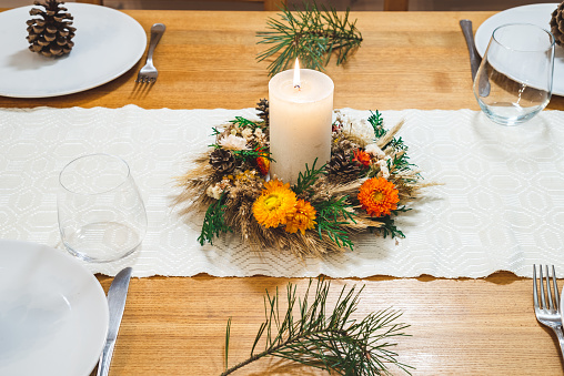 Fully set table with plates and cutlery, decorated with hand crafted Christmas wreath.