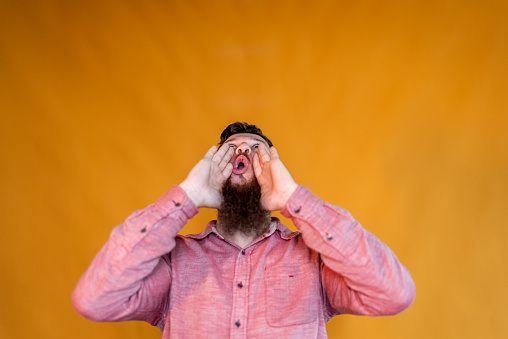 Mid adult man shouting on an orange background