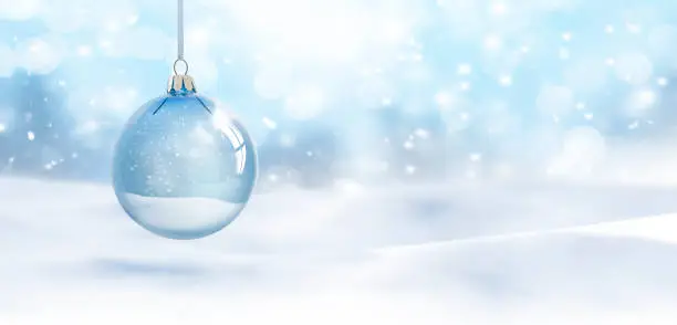 Photo of Transparent Christmas ball hanging in front of blurred snow background