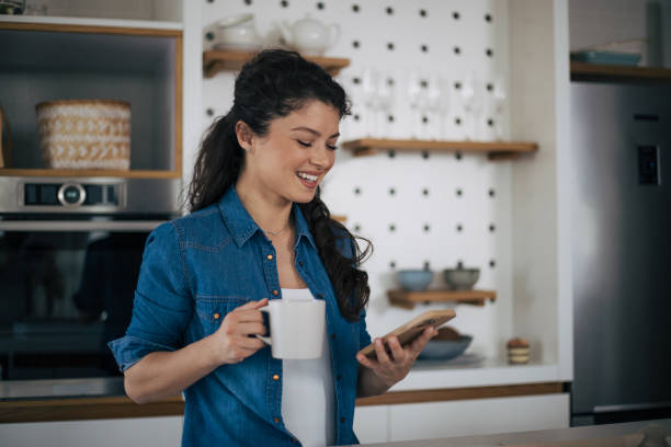 istock Beautiful woman in kitchen using phone 1444474955