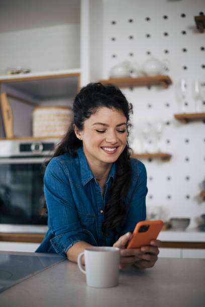 istock Beautiful woman in kitchen using phone 1444475023