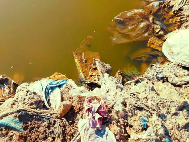 Polluted water with plastic litter and industrial waste dumping remains landfill and house hold garbage trash. Polluted-water, water-pollution, dirty-water closeup view image picture stock photo