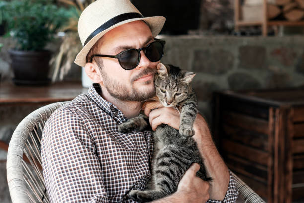 istock Man in straw hat and sunglasses hugging his cat. 1444475179