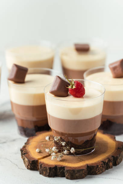 istock Layered dessert Trifles in a transparent glass.  Sponge biscuit and three chocolate mousse layers. Chocolate souffle trifle cake in individual disposable transparent cups. White background 1444482952