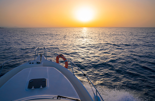 Sunrise or sunset sailing boating in the ocean sea orange sky and blue water in vacations