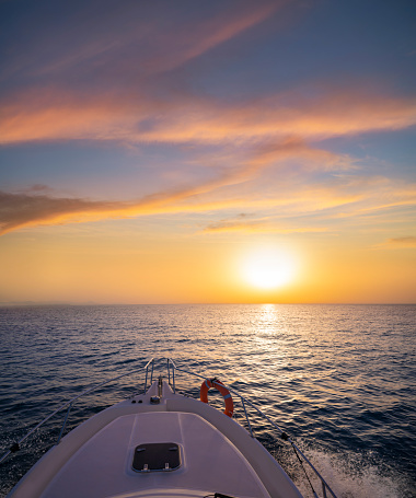 Sunrise or sunset sailing boating in the ocean sea orange sky and blue water in vacations