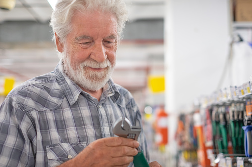 Senior man makes purchases in a hardware store chooses tools for repair or improvement home