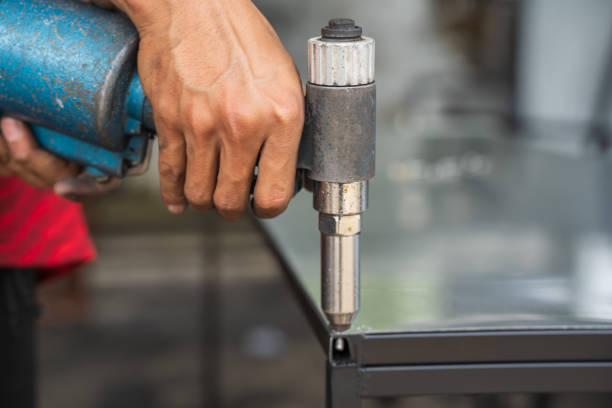 An industrial worker uses an air pop rivet gun to fasten workpieces with aluminum nails. An industrial worker uses an air pop rivet gun to fasten workpieces with aluminum nails. riveting stock pictures, royalty-free photos & images