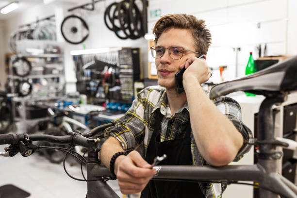 istock Young bicycle mechanic working on a customer bicycle talking on a phone 1444494992
