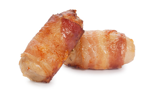 Studio shot of cooked sausages wrapped with bacon know as pigs in blankets cut out against a white background