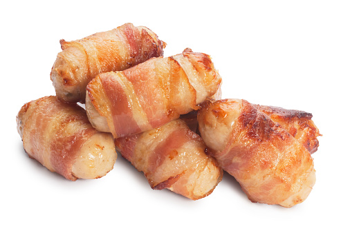 Studio shot of cooked sausages wrapped with bacon know as pigs in blankets cut out against a white background