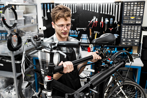 Young bicycle mechanic working on a customer bicycle