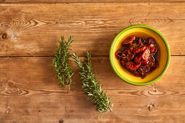 Bowl of semi dried tomatoes with rosemary plant stock photo