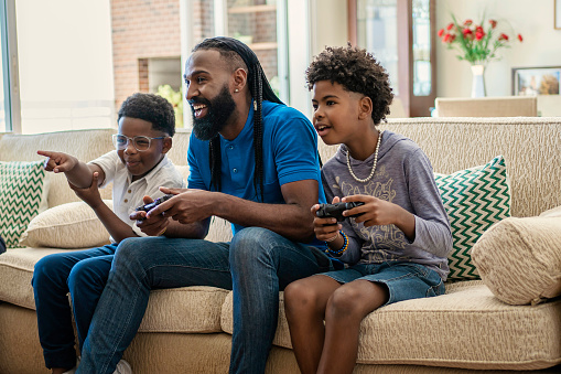 Father playing video game with his boys  on sofa