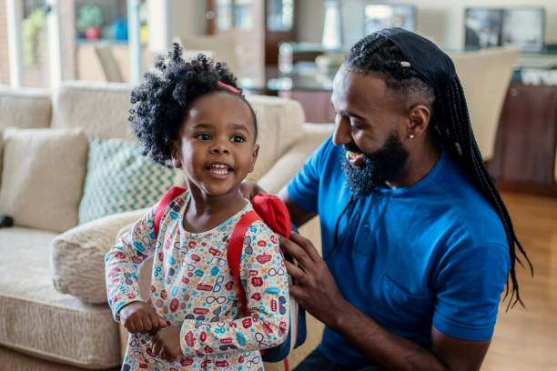 Father helping daughter to put lunch box at home