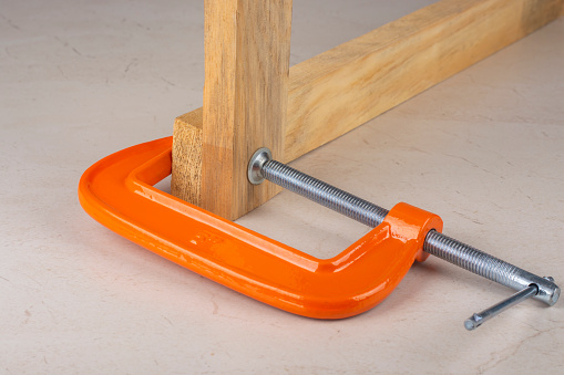The clamp compresses two wooden planks.